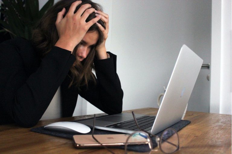 Stressed woman with her hands on her head looking at her laptop.